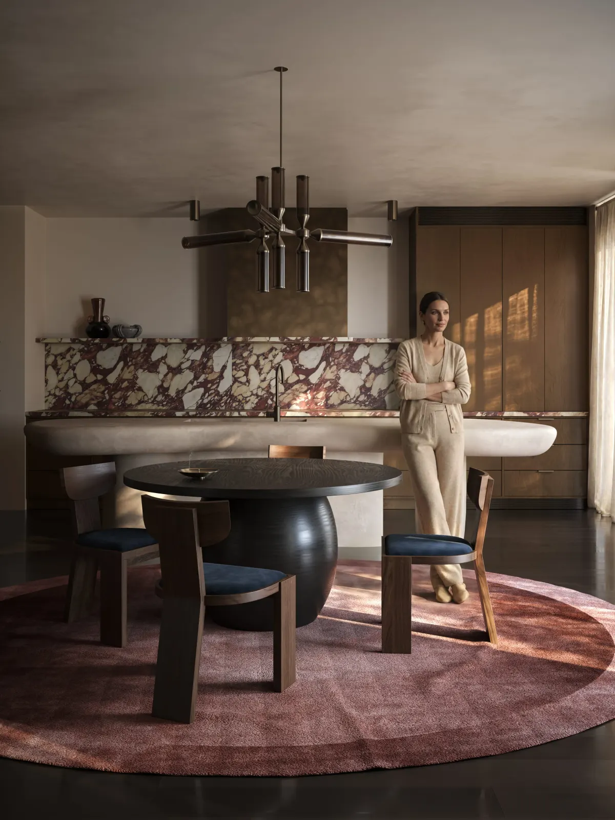 The same kitchen with a woman leaning on the island.
